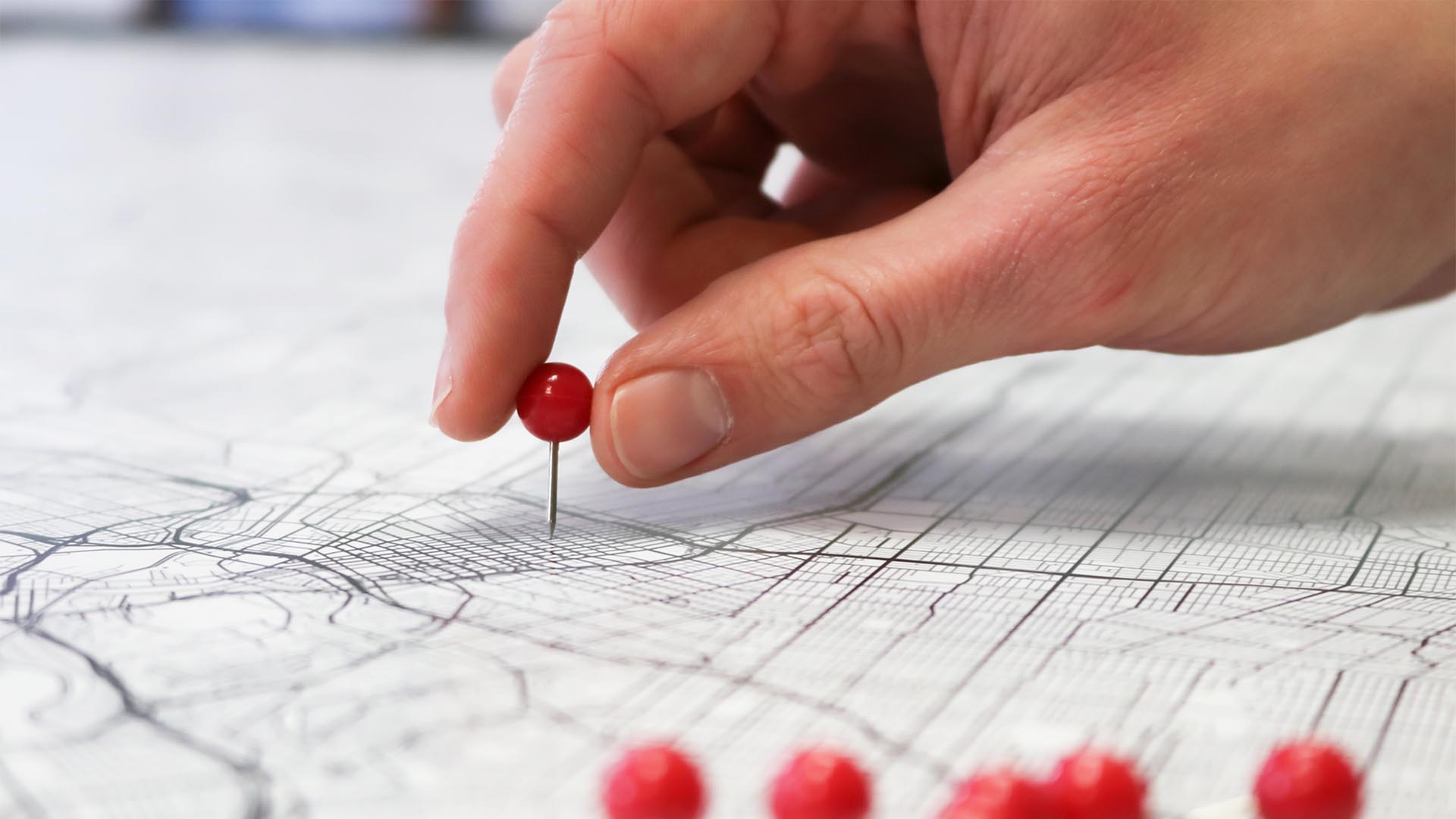 hand placing a pin on a street map