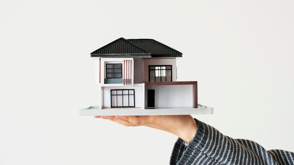 holding a model of a house